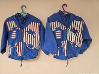 Both blue denim jackets hanging side by side showing overall style and flag panels