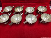 Eight matching silver-tone dragon-handle bowls on red cloth