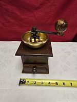 Front view showing wooden base, brass bowl, crank and measuring tape
