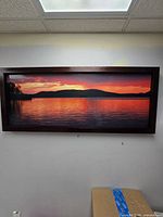 Front view of framed panoramic sunset lake photograph hung on wall