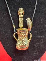 Full pendant on display bust showing cord, vessel shape, lid open