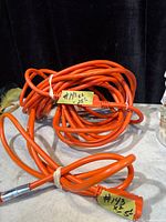 Coiled orange extension cords labeled 25' and 5' showing plug ends