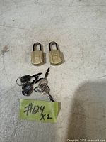 Two small brass-tone padlocks with four keys visible on a white surface