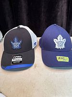 Front view of both caps showing logos, colours, brim stickers
