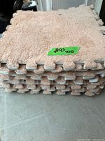 Stack of beige shag carpet foam tiles showing interlocking edges