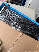 Keyboard inside torn box with protective plastic