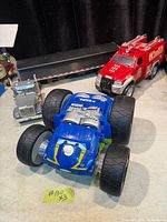 Group shot showing blue Tonka monster truck, red Tonka fire pickup, silver semi tractor and black trailer