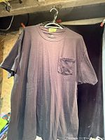 Full view of one dark Hanes pocket t-shirt on hanger