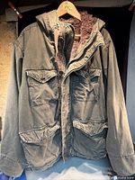 Front view of jacket showing pockets, zipper, snaps, hood