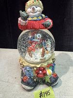 Front view of snow globe showing exterior snowman topper and interior scene