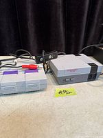 Both consoles side by side with controllers and cables visible
