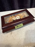 Wooden musical jewellery box closed showing glass lid with pressed flowers