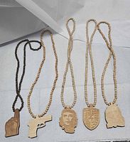 All five wooden bead necklaces laid out showing pendants