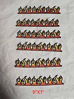 Six identical embroidered flame patches displayed on fabric background