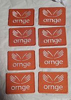 Full set of eight identical Ornge patches arranged in two columns on fabric surface
