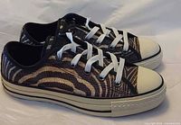 Left side view of both sneakers showing zebra print upper and laces