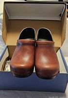 Front view of both clogs standing in open box