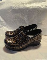 Left side view of both clogs showing leopard patent upper and heel