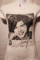 Front view of T-shirt showing Harry Styles graphic, 1D logo, size small tag