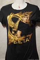 Front view of black t-shirt with Peeta graphic and size indicator