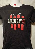 Front view of black Green Day graphic T-shirt showing logo and size tag