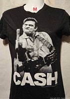 Front view of black girls T-shirt with Johnny Cash graphic and CASH text