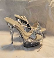 Side view of both clear platform heels showing mirror strap and height