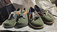 Both pairs of green Kickers kids shoes side by side showing uppers and laces