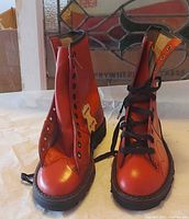 Front view of pair red leather lace-up boots showing uppers, tongue, eyelets and soles
