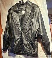 Front view of black leather jacket on hanger
