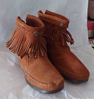 Front view of both boots showing fringe, braid, conchos and toe stitching