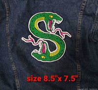 Front view showing entire embroidered snake S patch on denim background with size text
