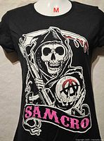 Front view of black SAMCRO graphic T-shirt showing full design and size label M