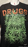 Front view of black T-shirt showing text and cannabis leaf design