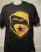 Front view of black T-shirt showing shield graphic with eagle and star, size tag indicated L