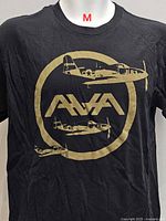 Front view of black T-shirt with gold AVA aircraft graphic, size marker M