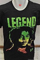 Front view of black graphic T-shirt showing LEGEND text and Bob Marley portrait