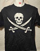 Front view of black T-shirt showing skull and crossed sabres graphic and size label M