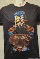 Front view of black Superman graphic T-shirt on mannequin, size small marked at collar