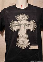 Front view of black T-shirt size S with cross face graphic and price tag$24.99