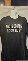 Front view of black T-shirt with "GOD IS COMING! LOOK BUSY" text