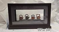 front view showing four teapots in case, dimension noted 10 x 16 inches