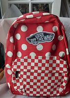 Front view showing polka-dot pattern, checkerboard pocket, and Vans patch
