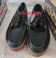 Pair of black Vans moc-toe shoes with tag, size 13 text overlay