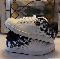 Side view of both shoes showing white upper with black graphics