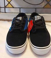 Frontal view of the pair showing black suede toe, blue sides, white soles, and hang tag
