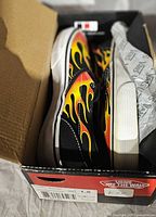 Shoes in original Vans box showing side flame graphic