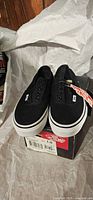 Pair of black Vans Era Laceless shoes on top of box
