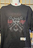Front view of black Vans T-shirt with wolf and guitars graphic, size XL tag visible.