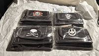 Four packaged black nylon wallets with distinct skull graphics